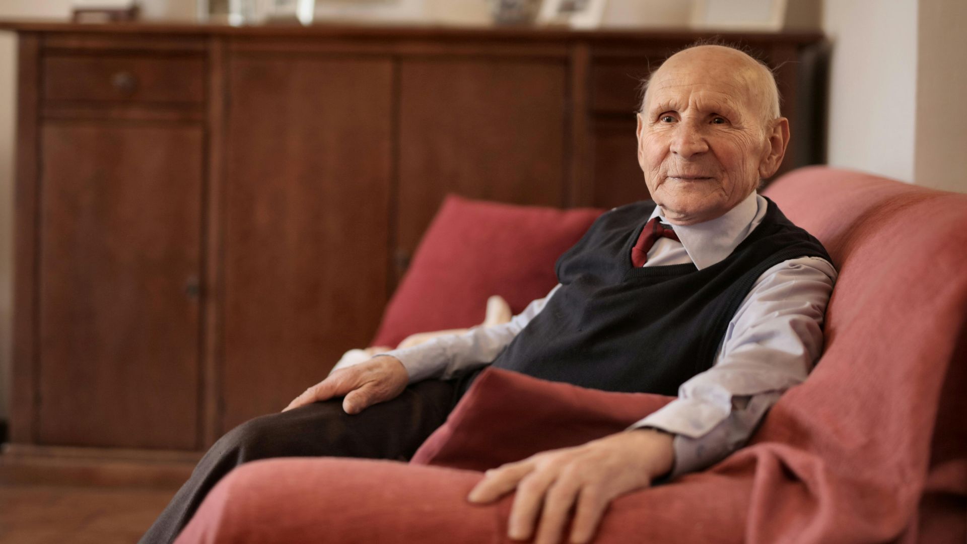 Senior man sitting comfortably on a sofa in a warm and inviting living room.
