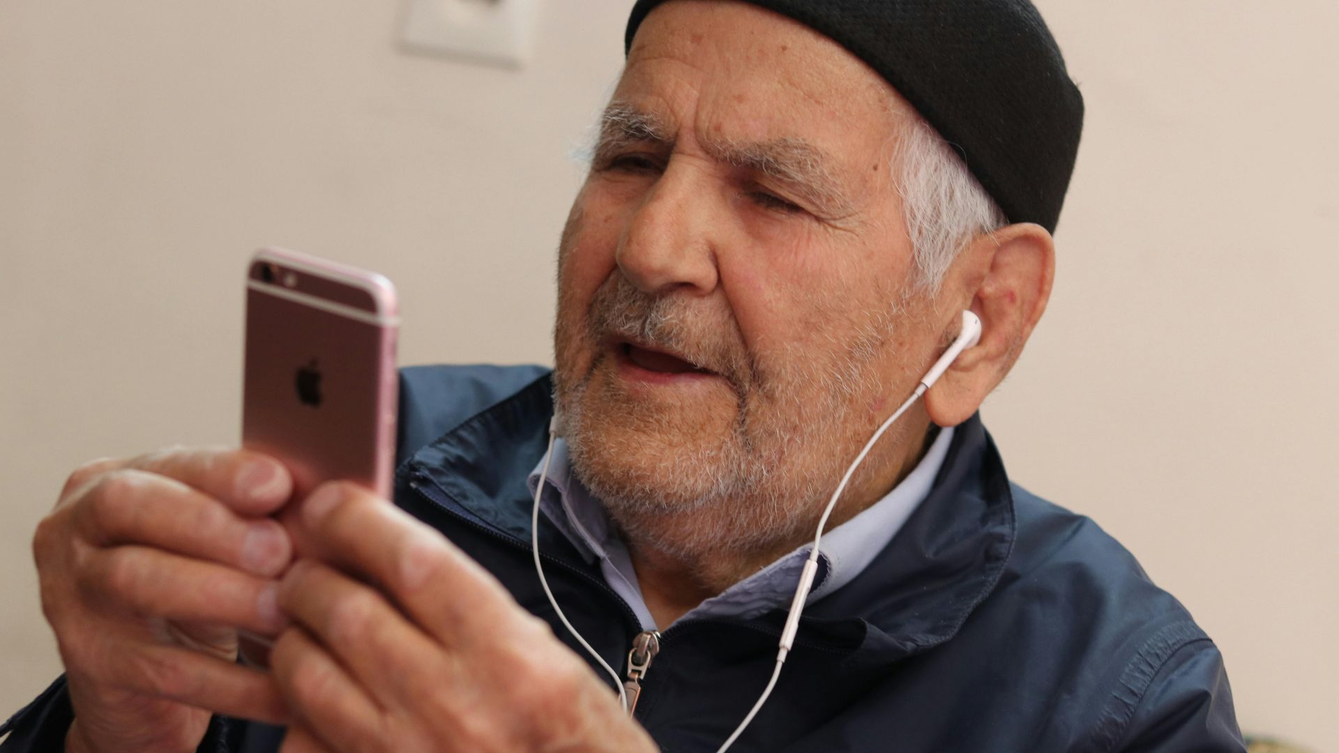 Senior man with headphones enjoying music on his smartphone indoors.