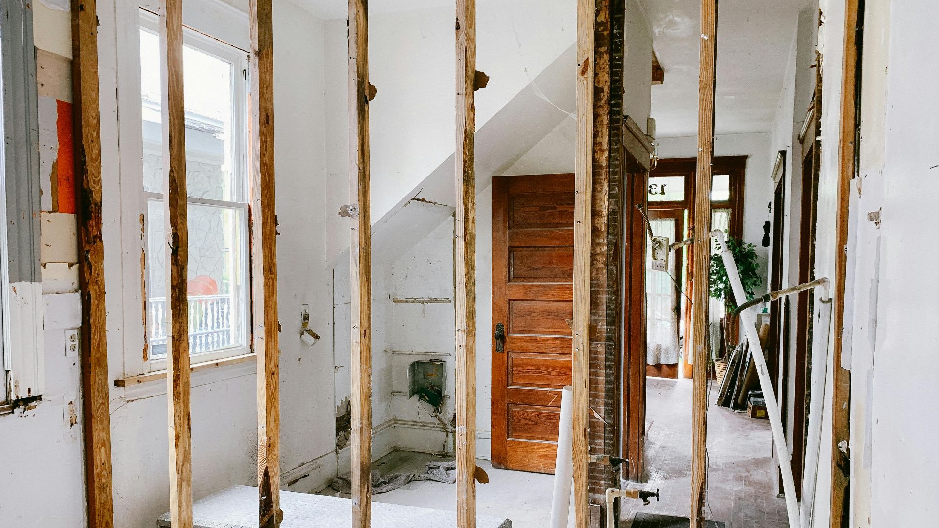 Interior view of a home under renovation with exposed wooden beams and door.