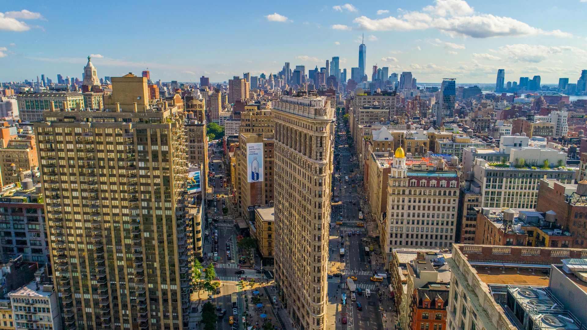 Stunning aerial view of New York City's skyline featuring the iconic Flatiron Building on a sunny day.