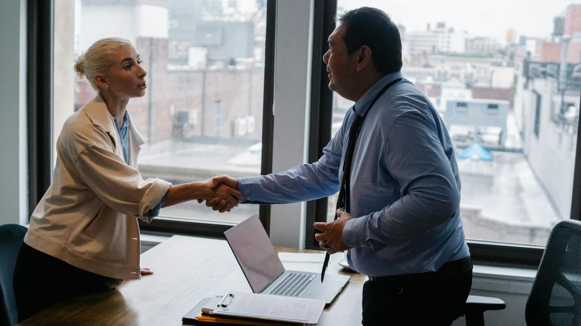 Professional handshake between two colleagues in a modern office setting.