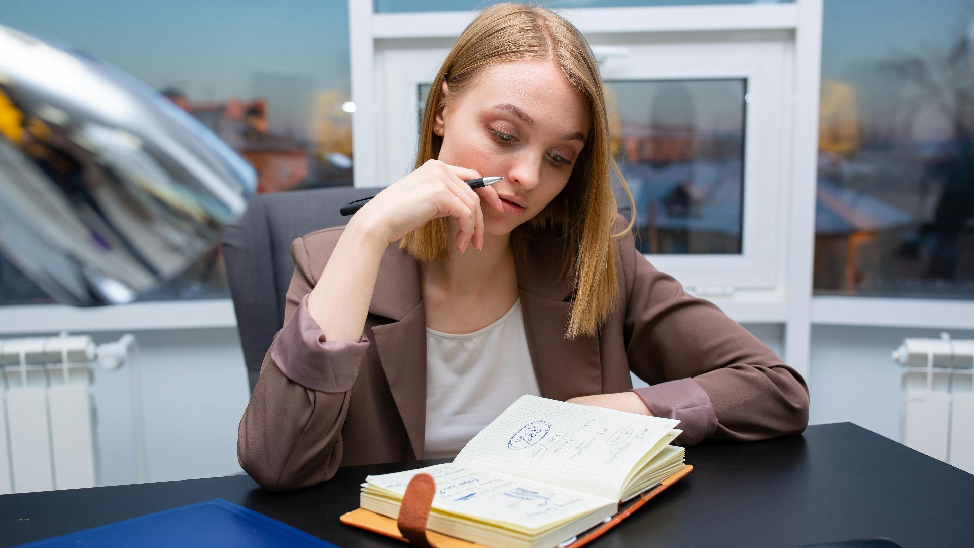 Thoughtful businesswoman planning her schedule at a modern office desk.