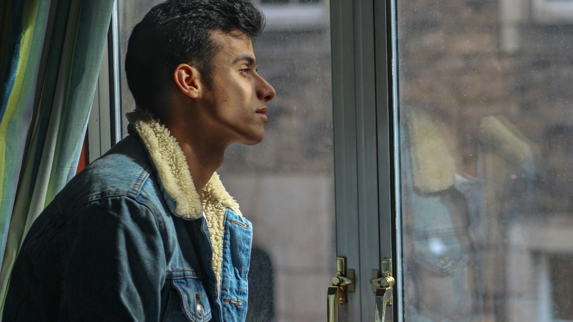 man in black jacket looking out the window