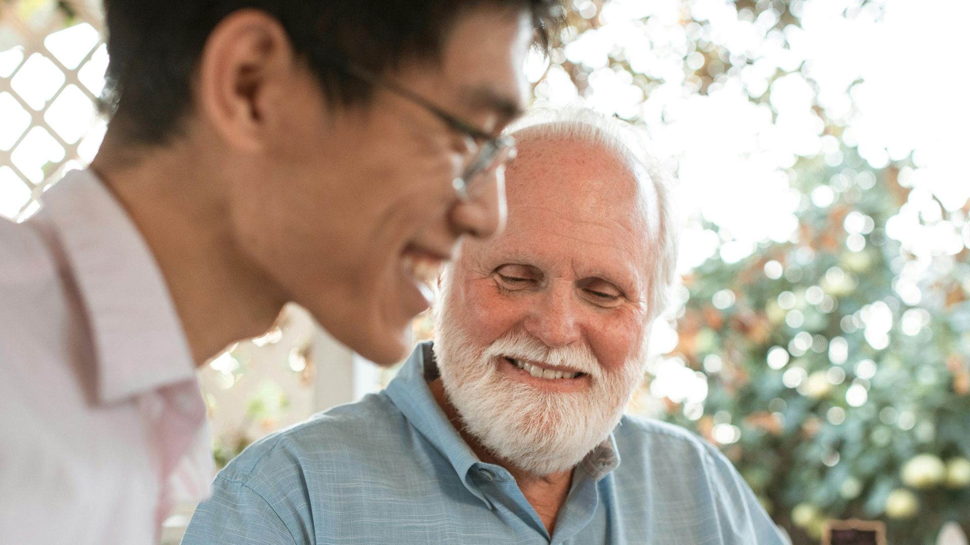 A senior man and an adult in a friendly conversation outdoors, enjoying a casual moment.