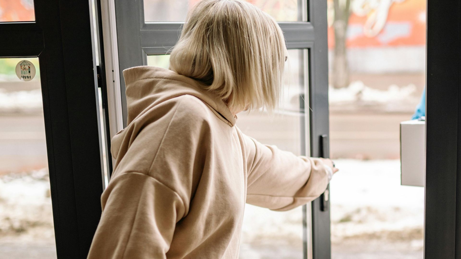 An elderly woman receives a parcel delivery at her doorstep, indoors.