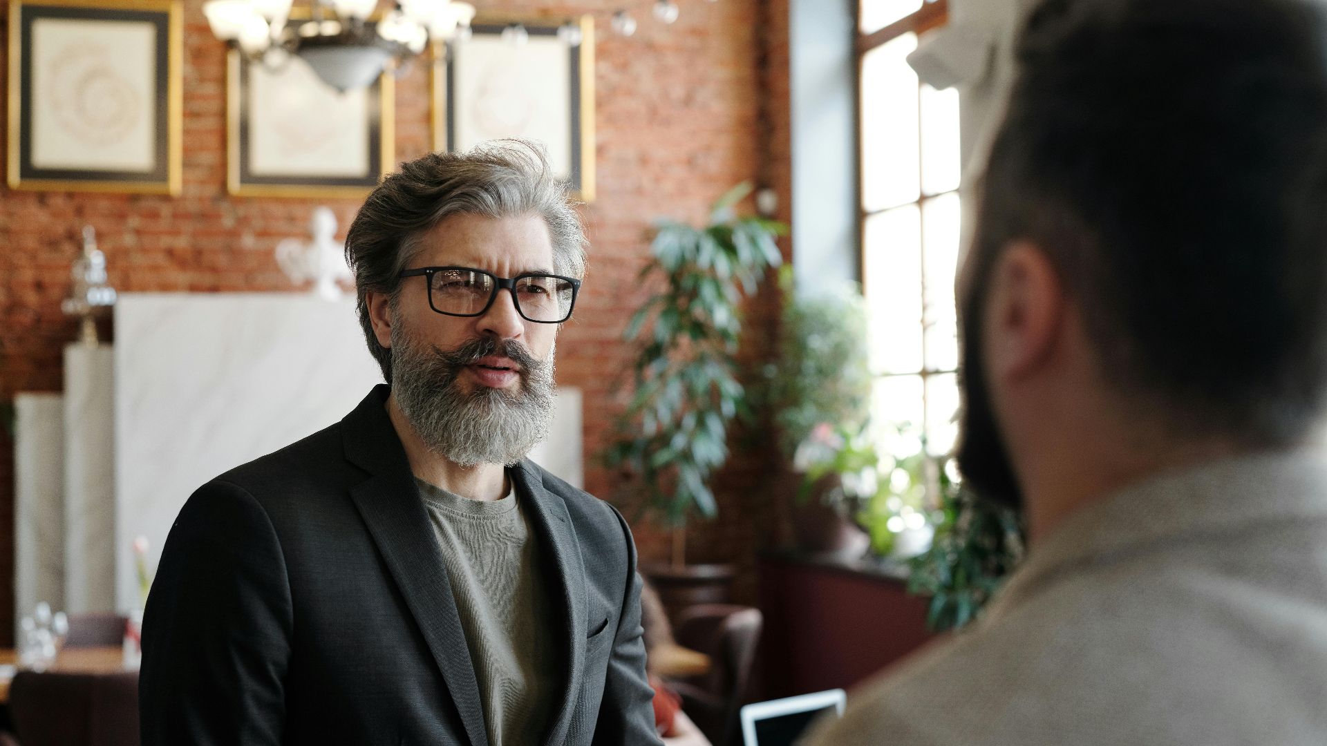 Senior man in suit with beard and eyeglasses in a business setting.