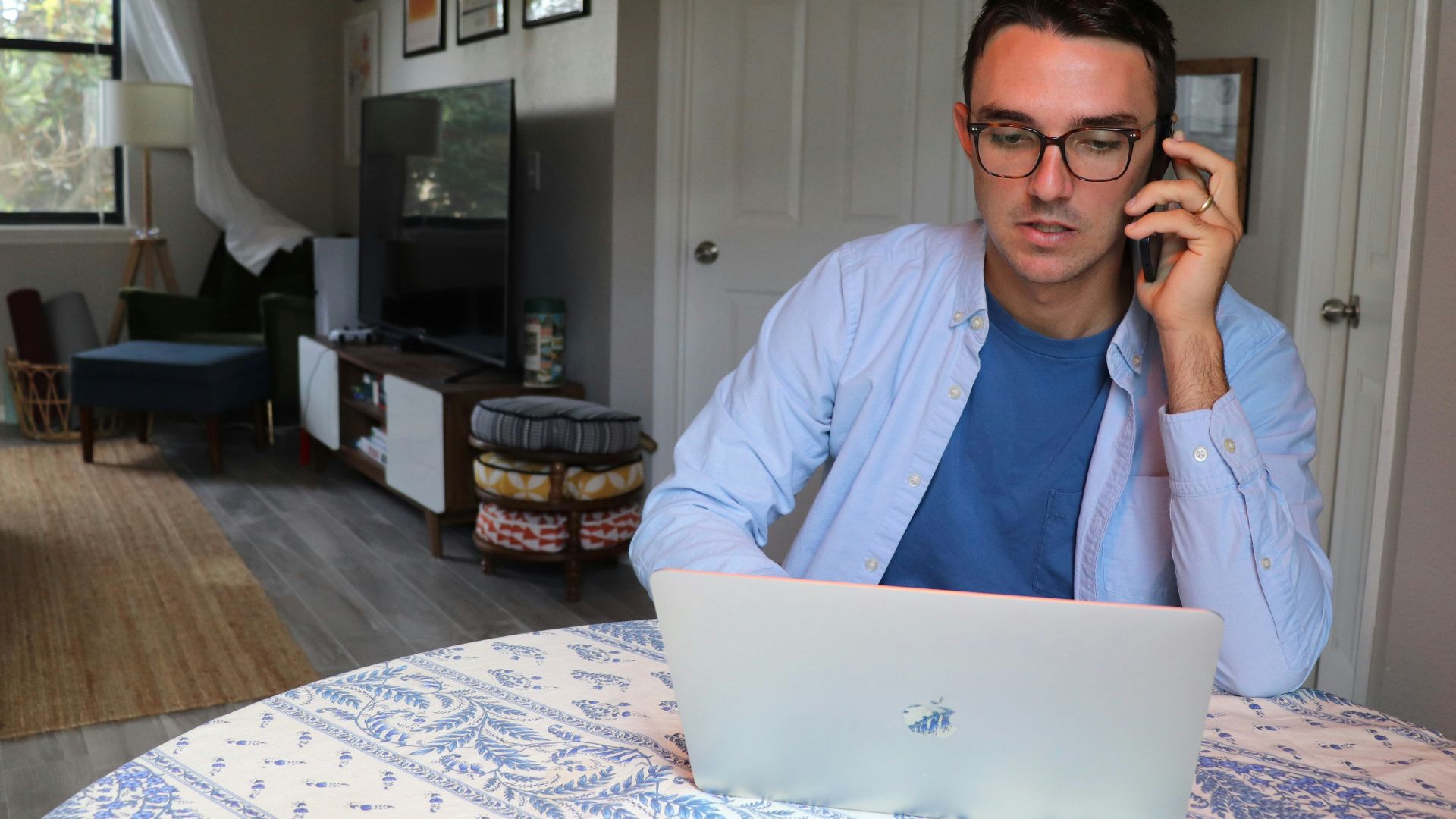 man in white dress shirt wearing eyeglasses sitting by the table using macbook