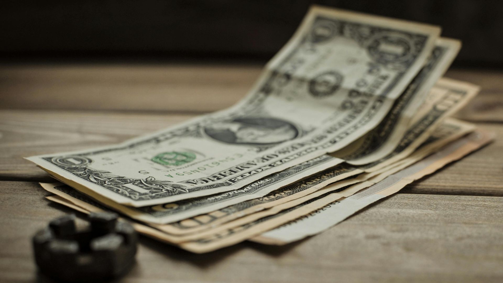 Close-up of US dollar bills on a wooden table, representing finance and commerce.