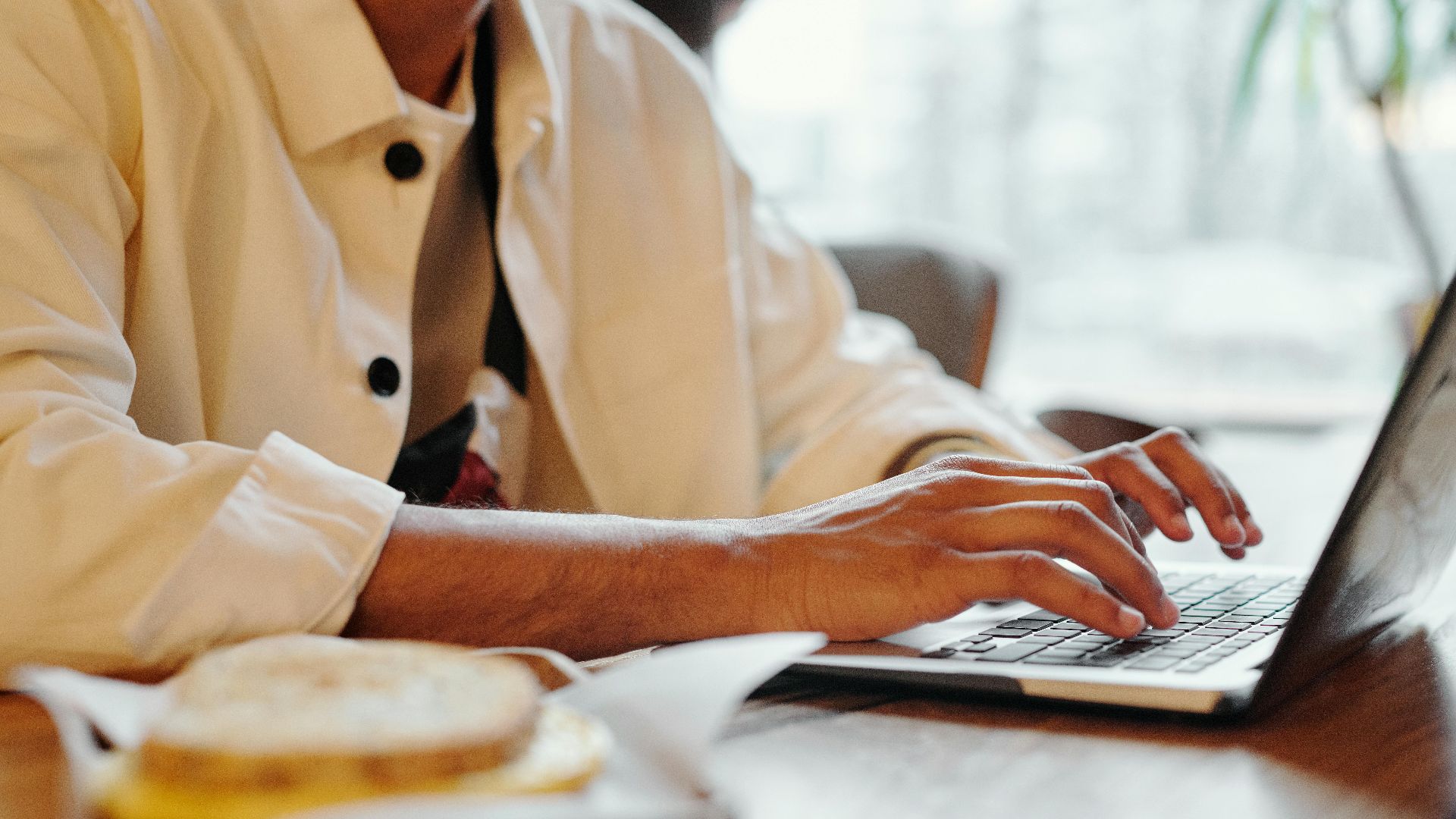 Close-up of hands typing on a laptop keyboard in a warm indoor environment with soft lighting.