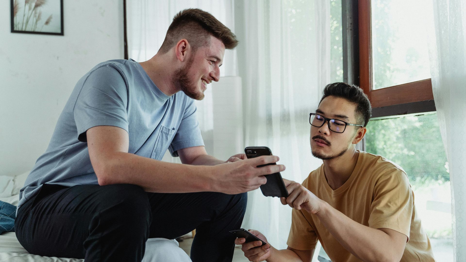 Two young men using smartphones, collaborating in a cozy room setting.