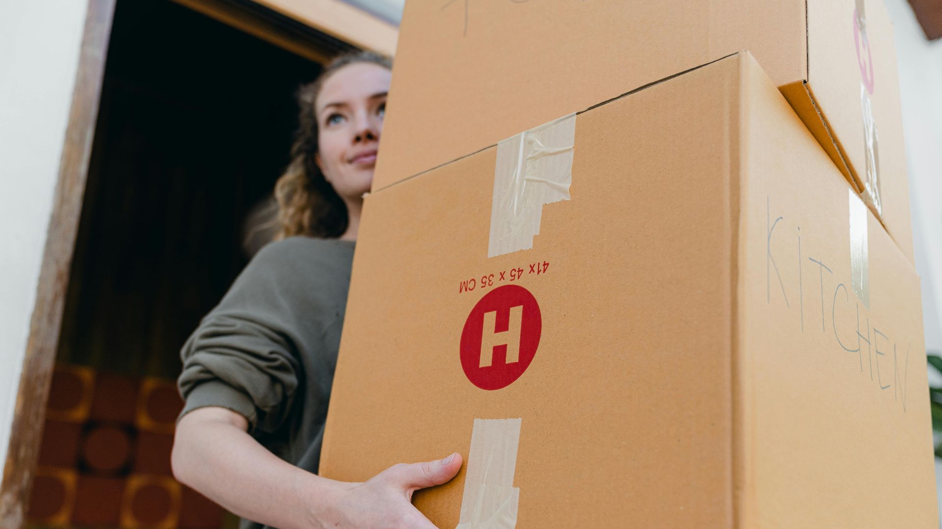 Confident young woman carrying cardboard boxes during a move out day.