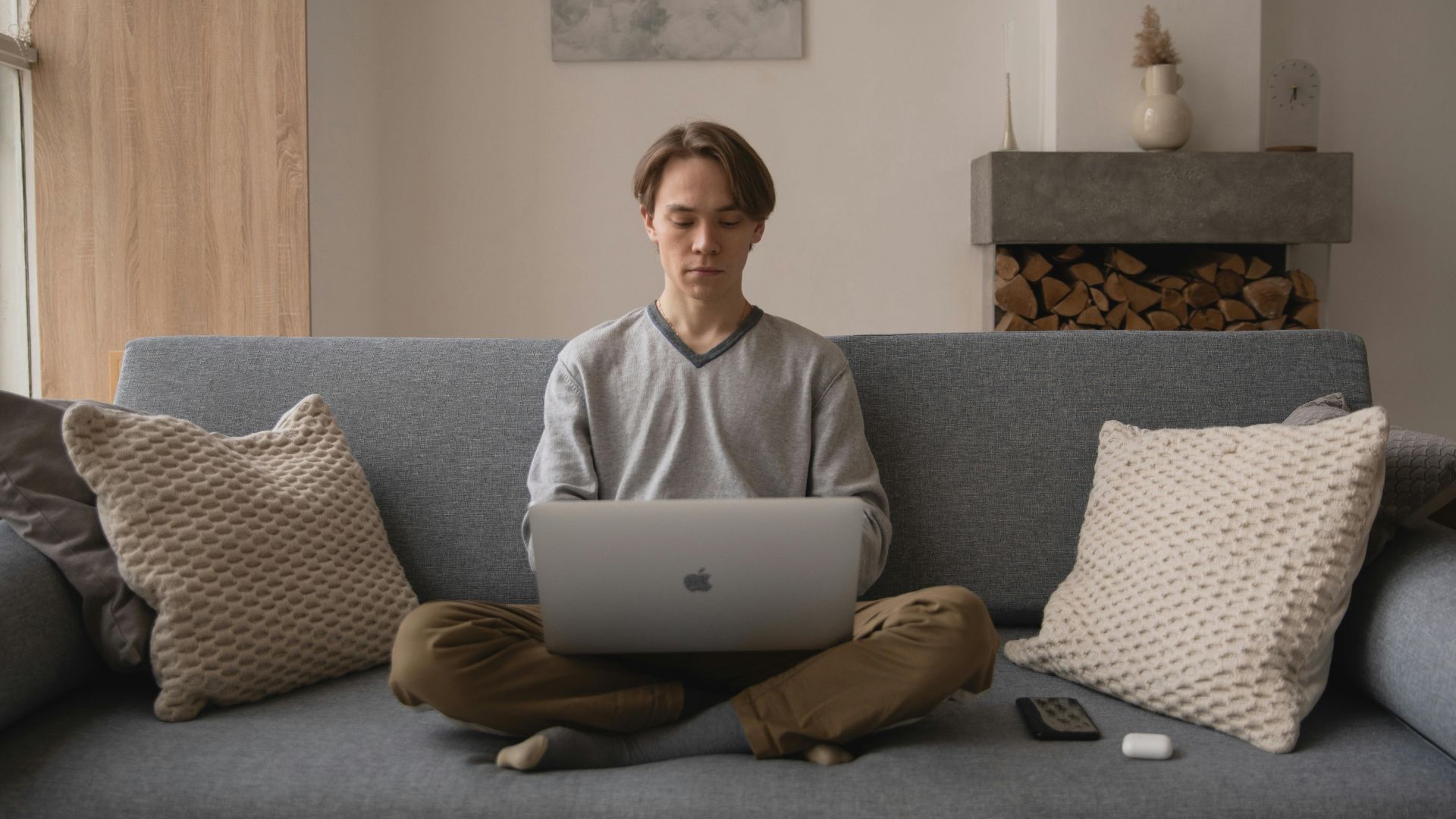 Man sitting on cozy sofa working remotely on laptop, showcasing modern digital lifestyle.
