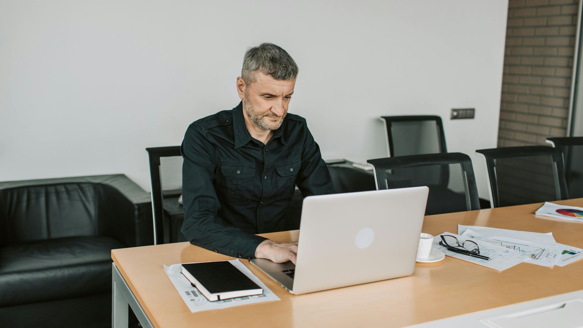 Mature man focusing on his laptop while working in a modern office environment.