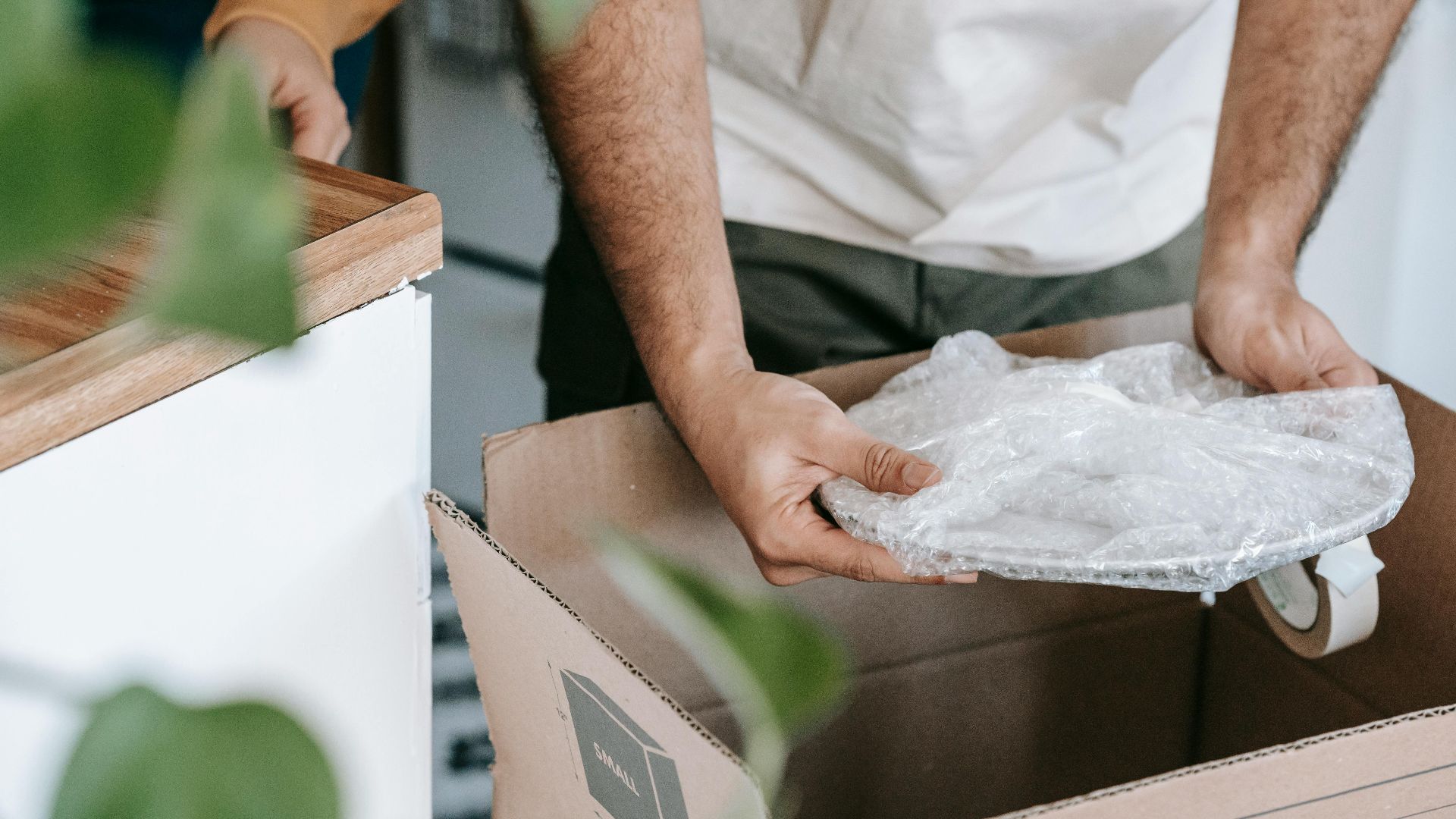 Man preparing dishes in a box for moving into a new home during the day.
