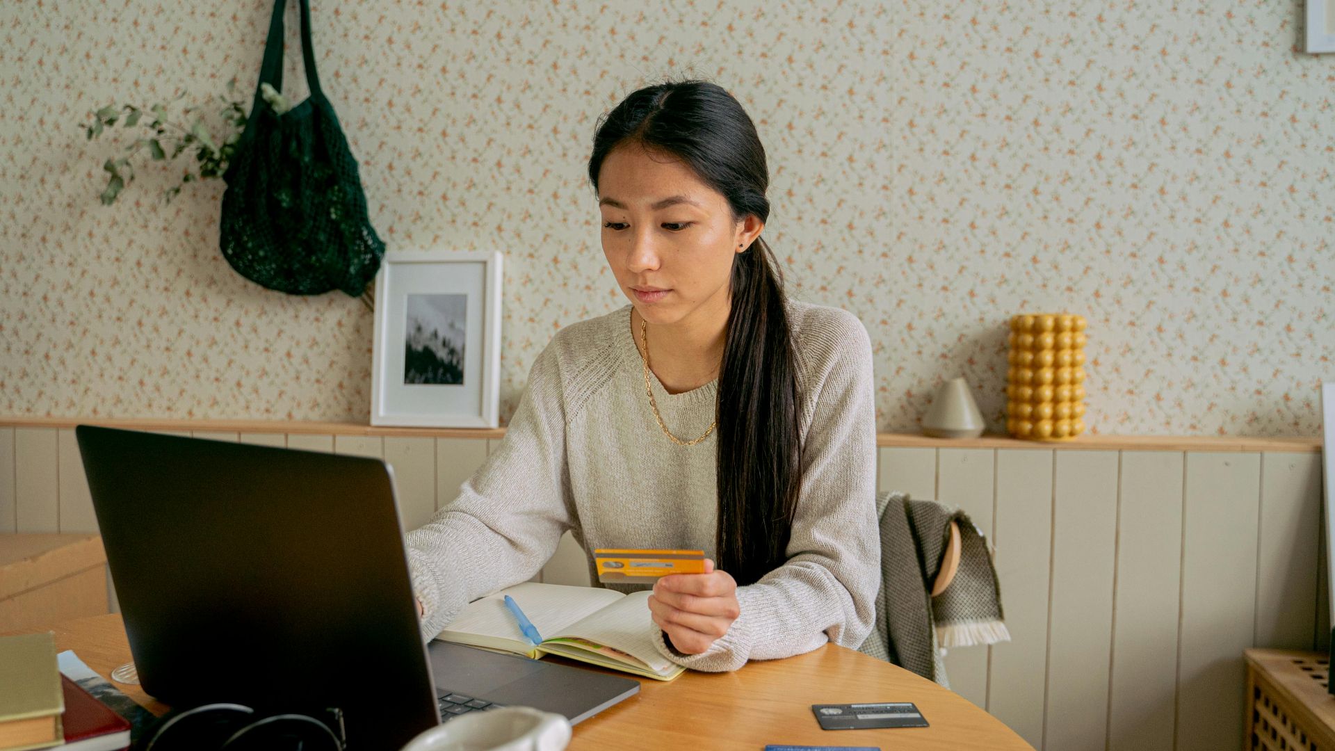 A woman using a laptop and credit card for online shopping at a cozy indoor setting.