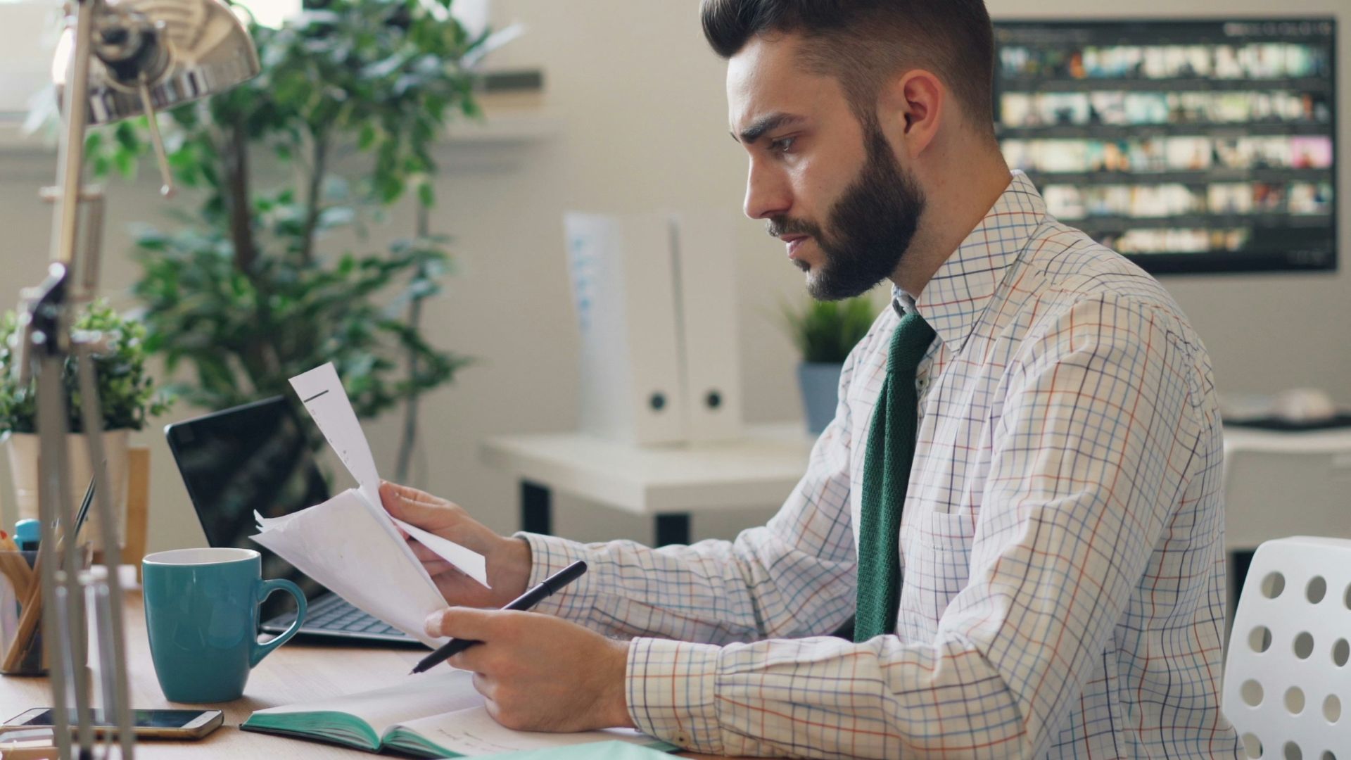 a man sitting at a desk with a laptop and papers