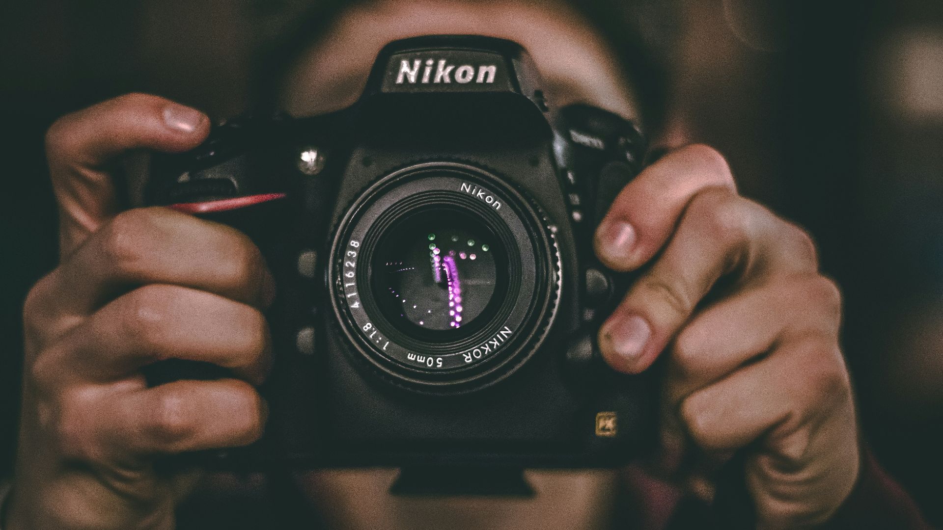 person's face being covered by Nikon DSLR camera