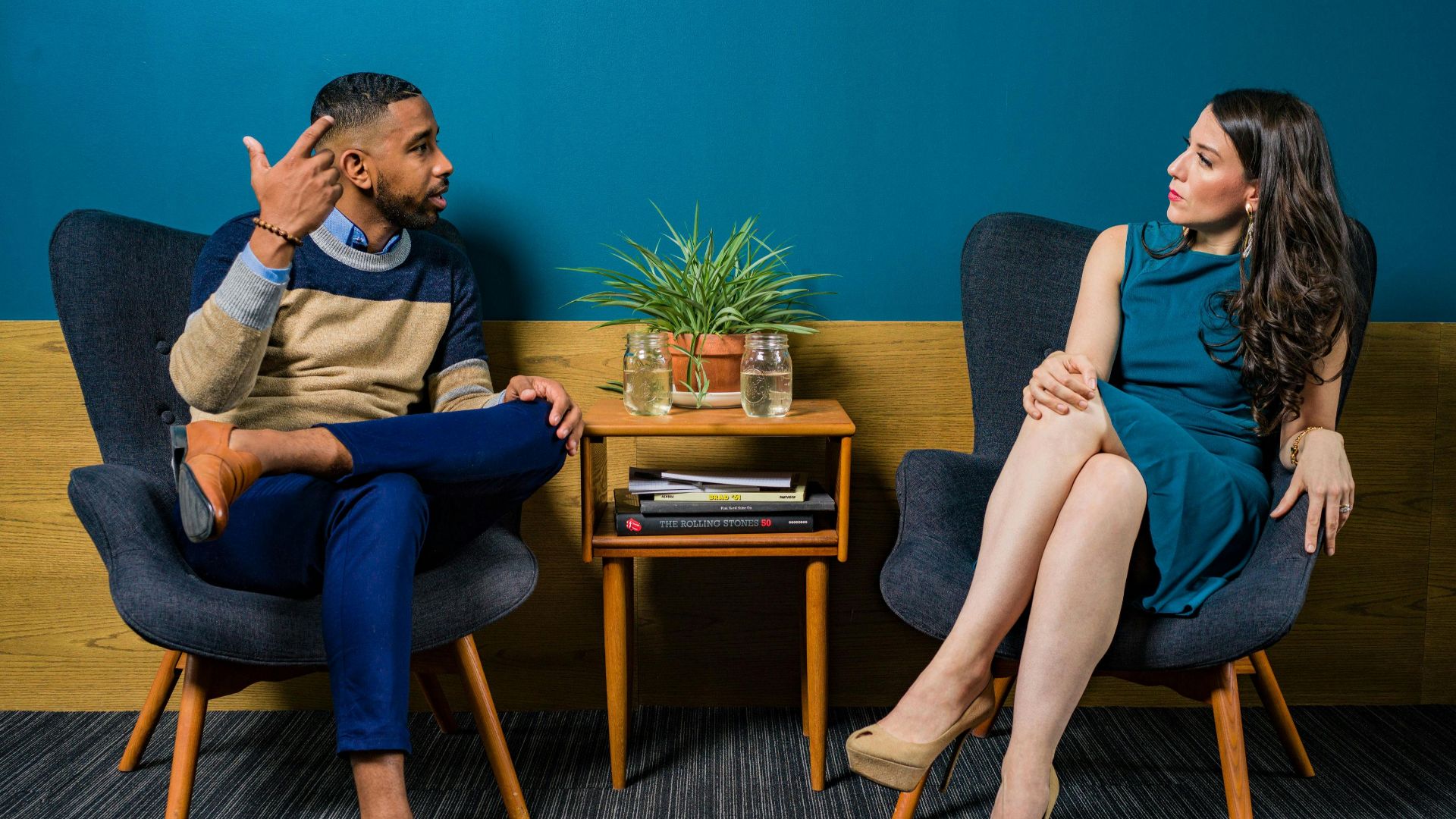 Two professionals in business attire engage in a thoughtful discussion sitting in a stylish, modern room.