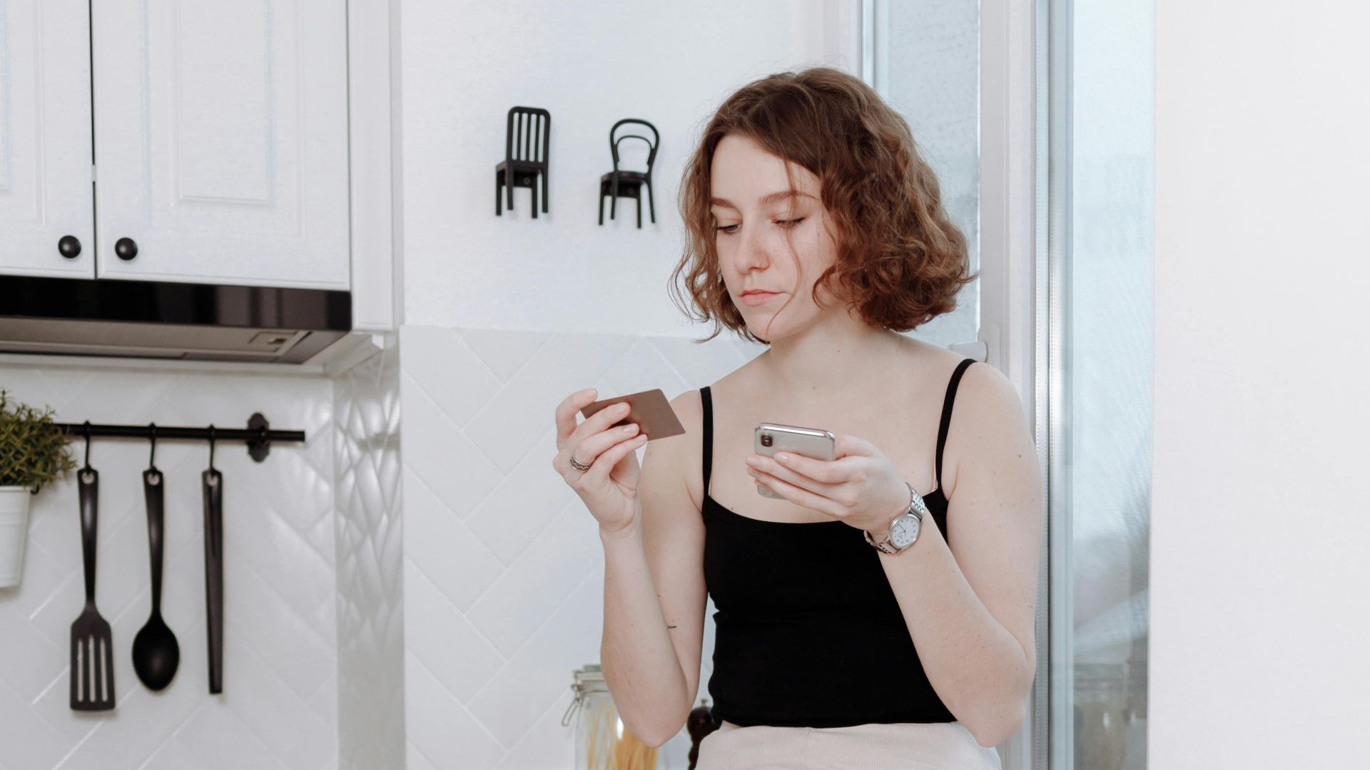 Young woman enjoying a cup of coffee while sitting in a stylish, modern kitchen.