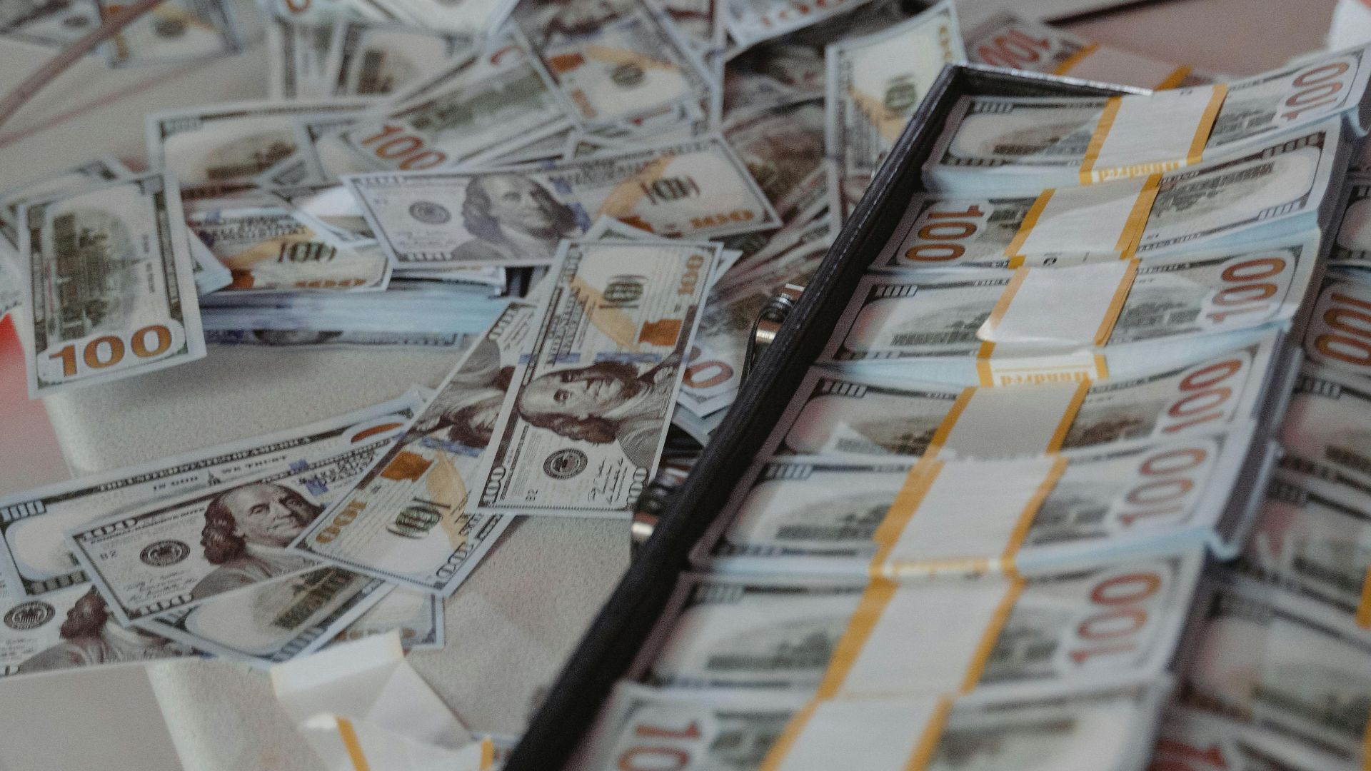 Large bundles of US dollar bills spread across a table, showcasing wealth.