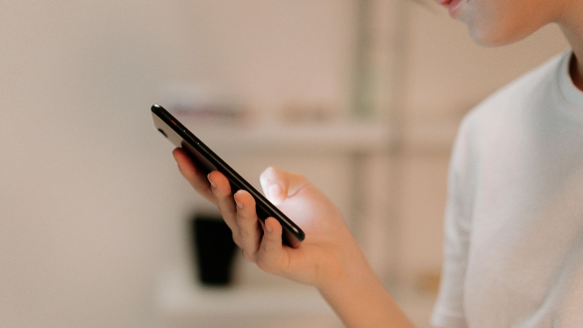 Close-up of a person using a smartphone indoors, focusing on hand and device.