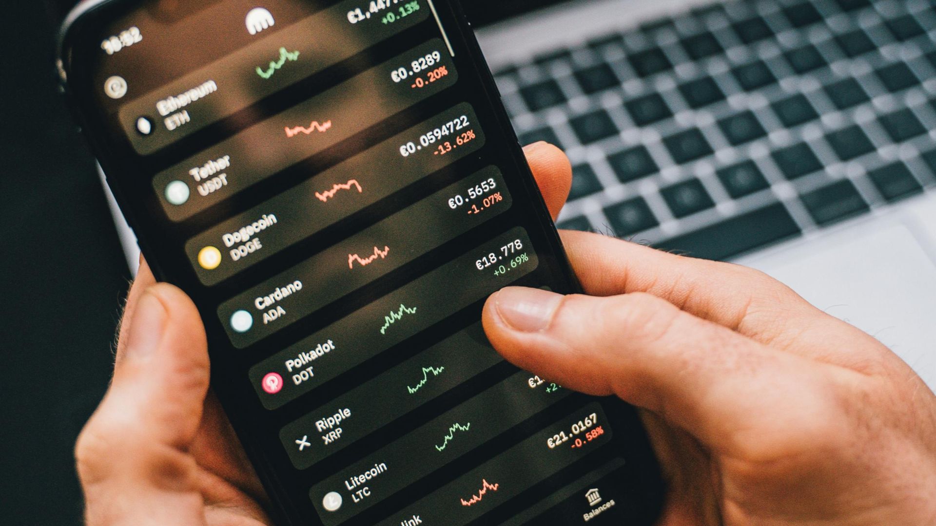 Hands holding smartphone with stock app, laptop displaying charts. Perfect for financial and technology themes.