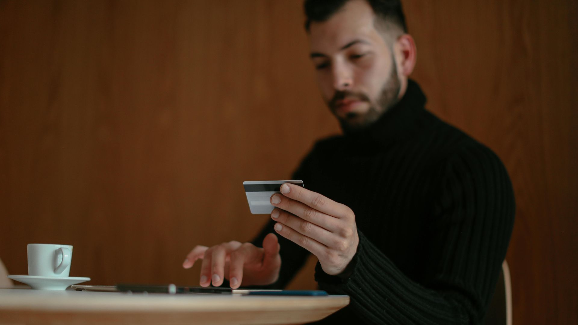 Focused man in café using tablet and credit card for online shopping.