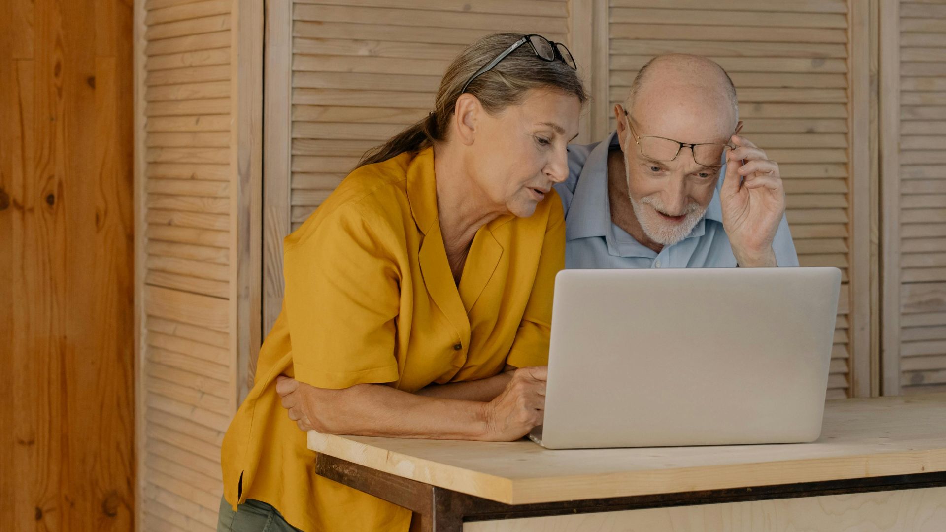 Elderly couple engaged with a laptop in cozy home setting.