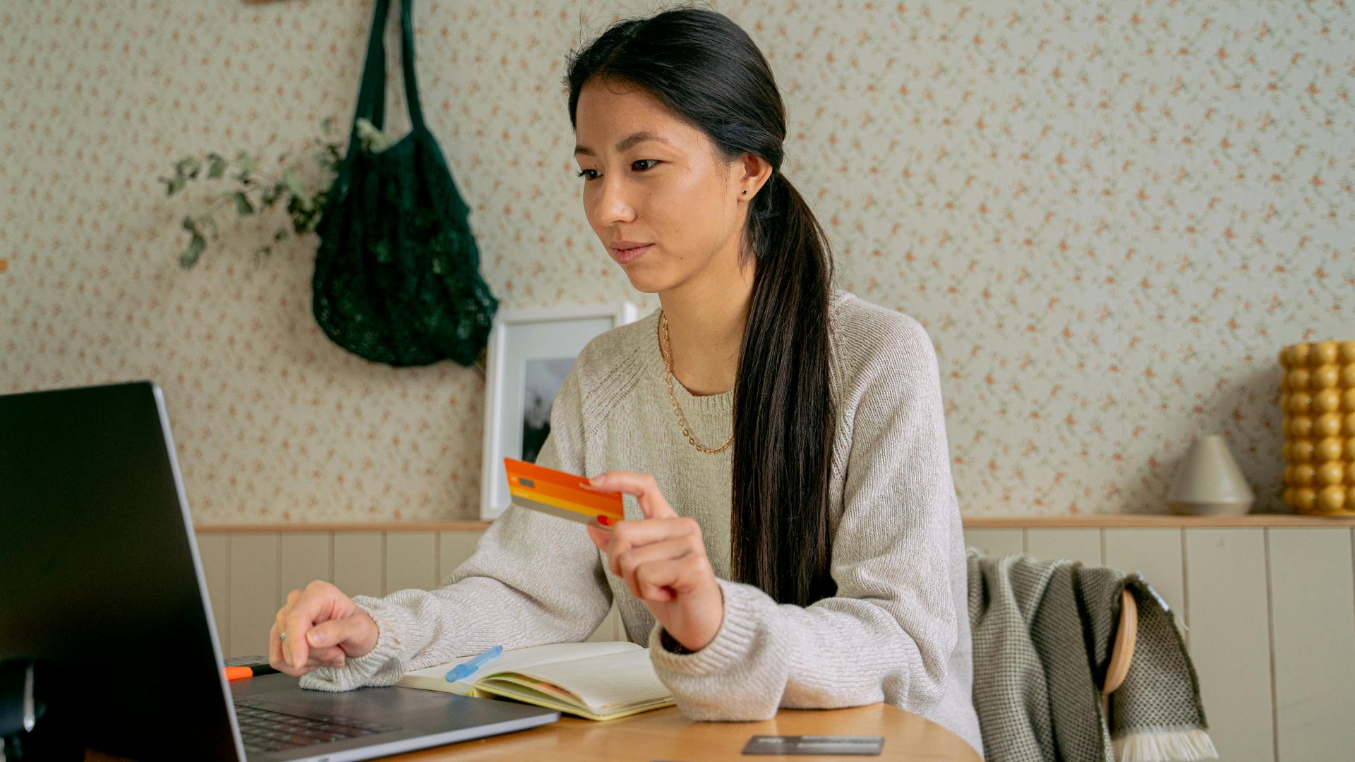 Young Asian woman using a laptop and credit card for online shopping at home.