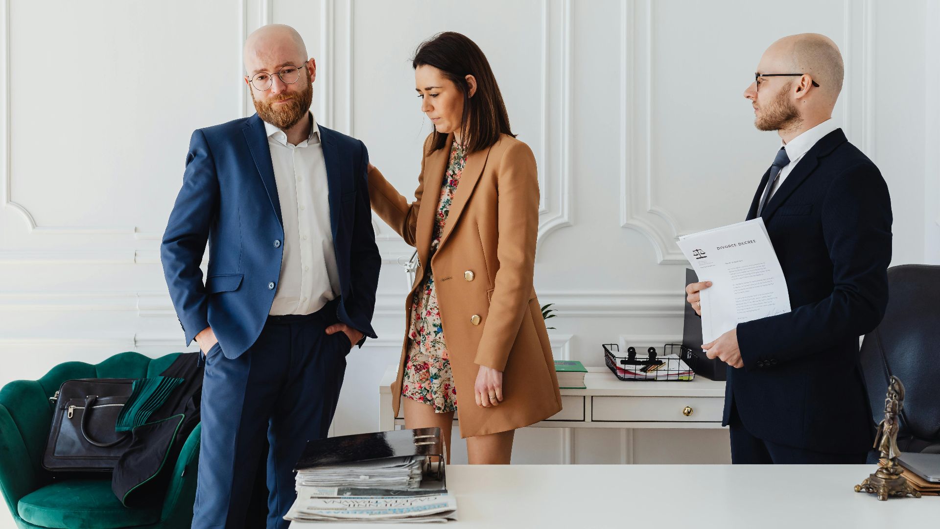 A couple with a lawyer in an office setting, reviewing divorce documents in formal attire.