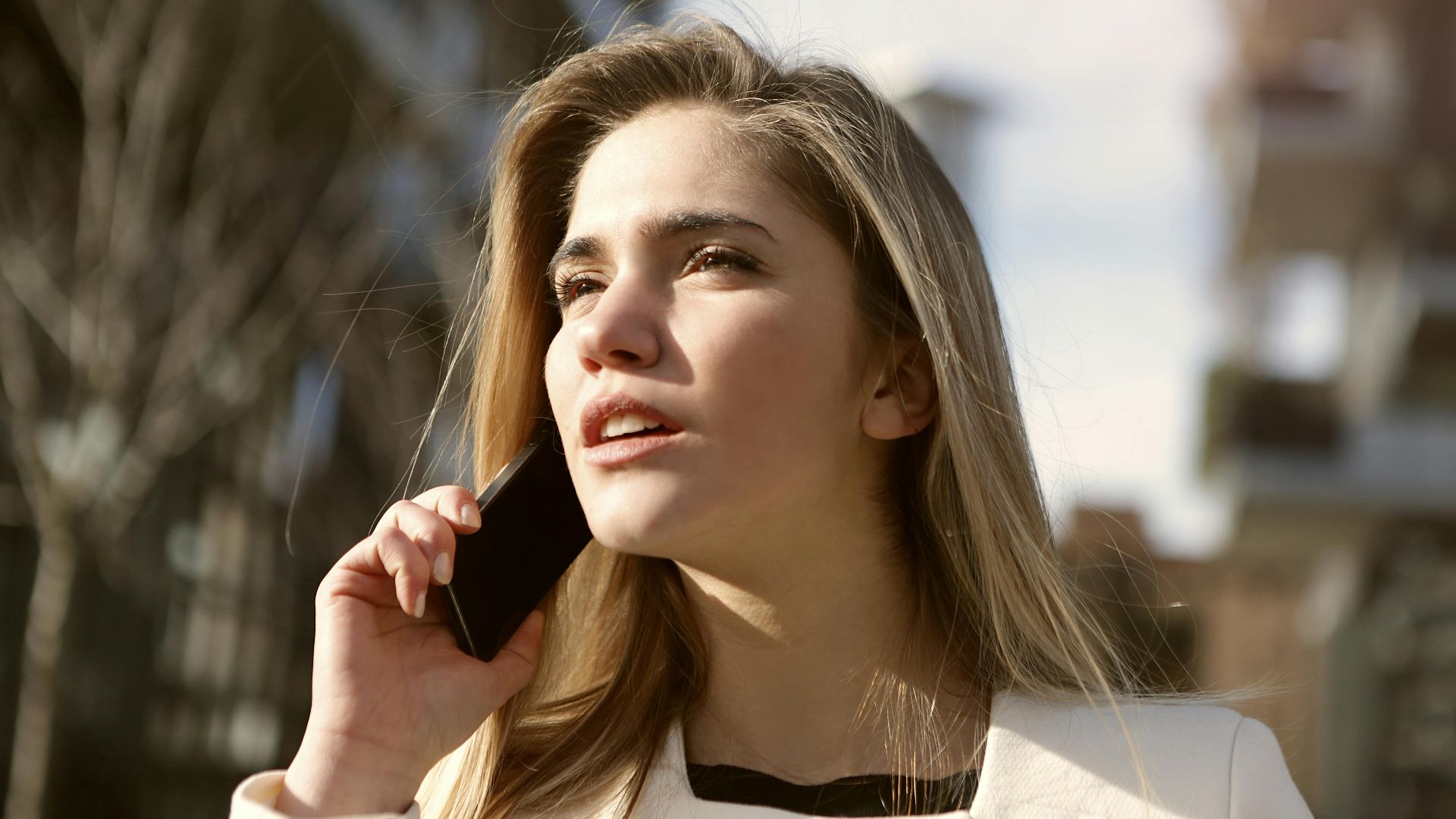 Young woman engaging in a phone call outdoors, capturing a moment of modern communication.
