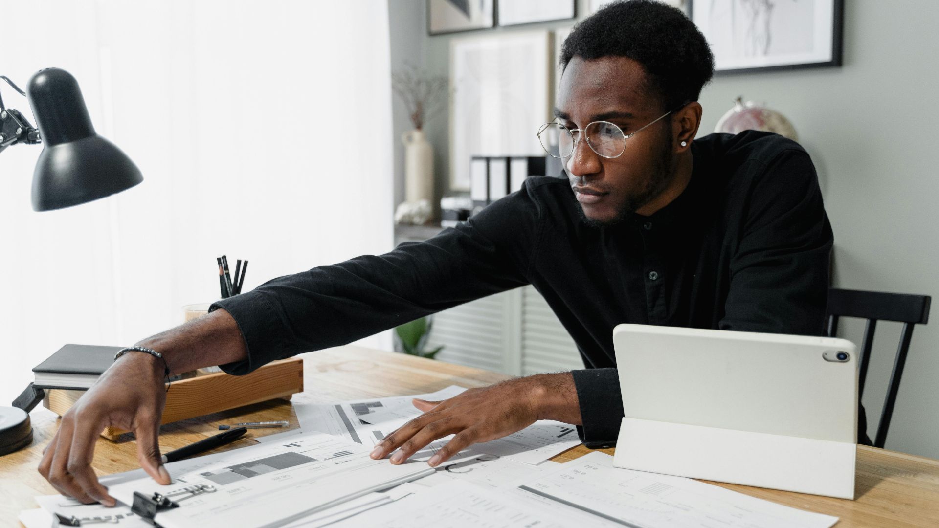 Business professional working at desk reviewing financial documents with digital tablet.