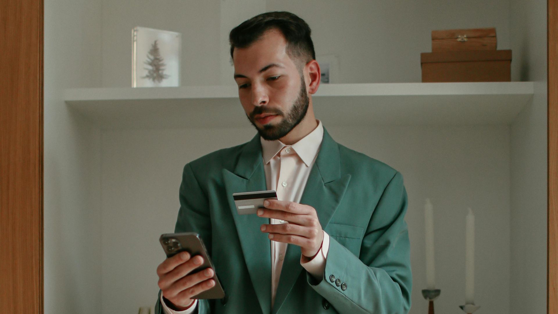 Barefoot man using smartphone and credit card for online shopping indoors. Modern lifestyle concept.