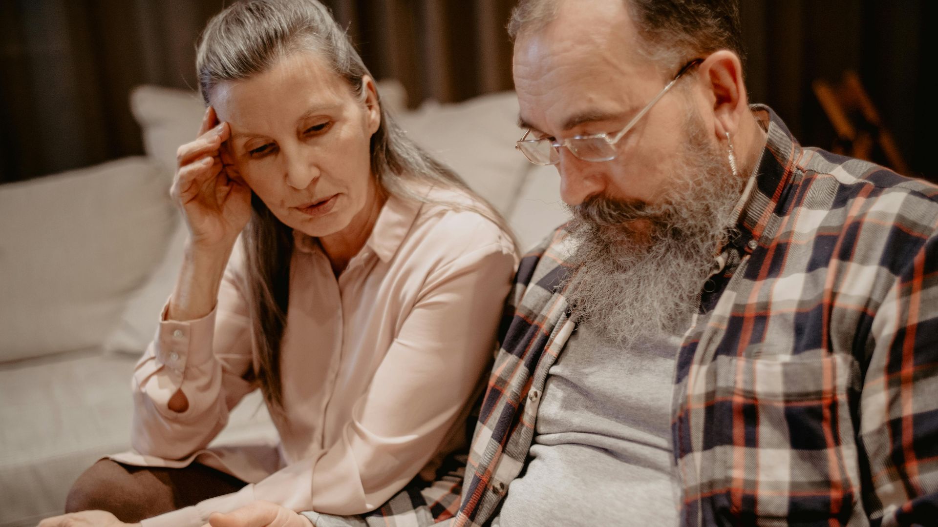 A senior couple reminisces while looking through a photo album at home, reflecting on cherished memories.