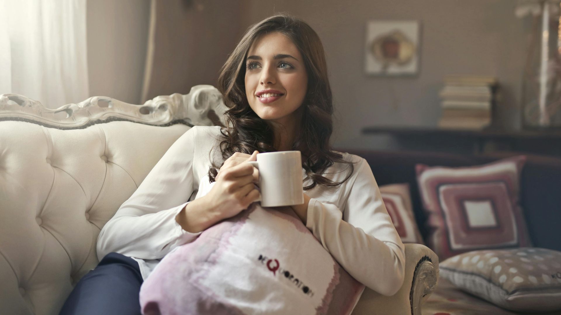 Woman relaxing with a cup of coffee on a sofa in a cozy living room.