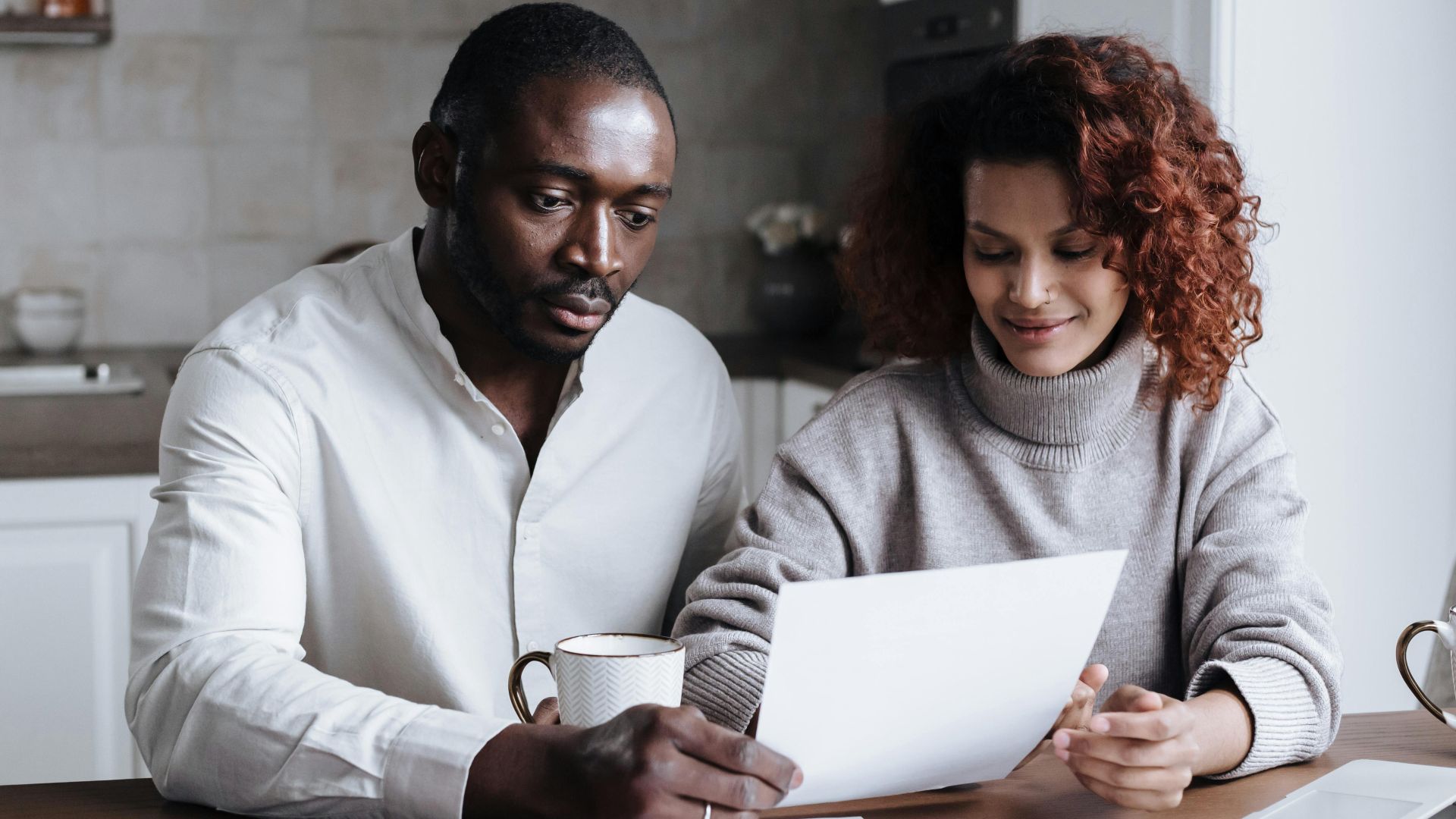 A couple reviews paperwork at a kitchen table, embodying teamwork and collaboration.