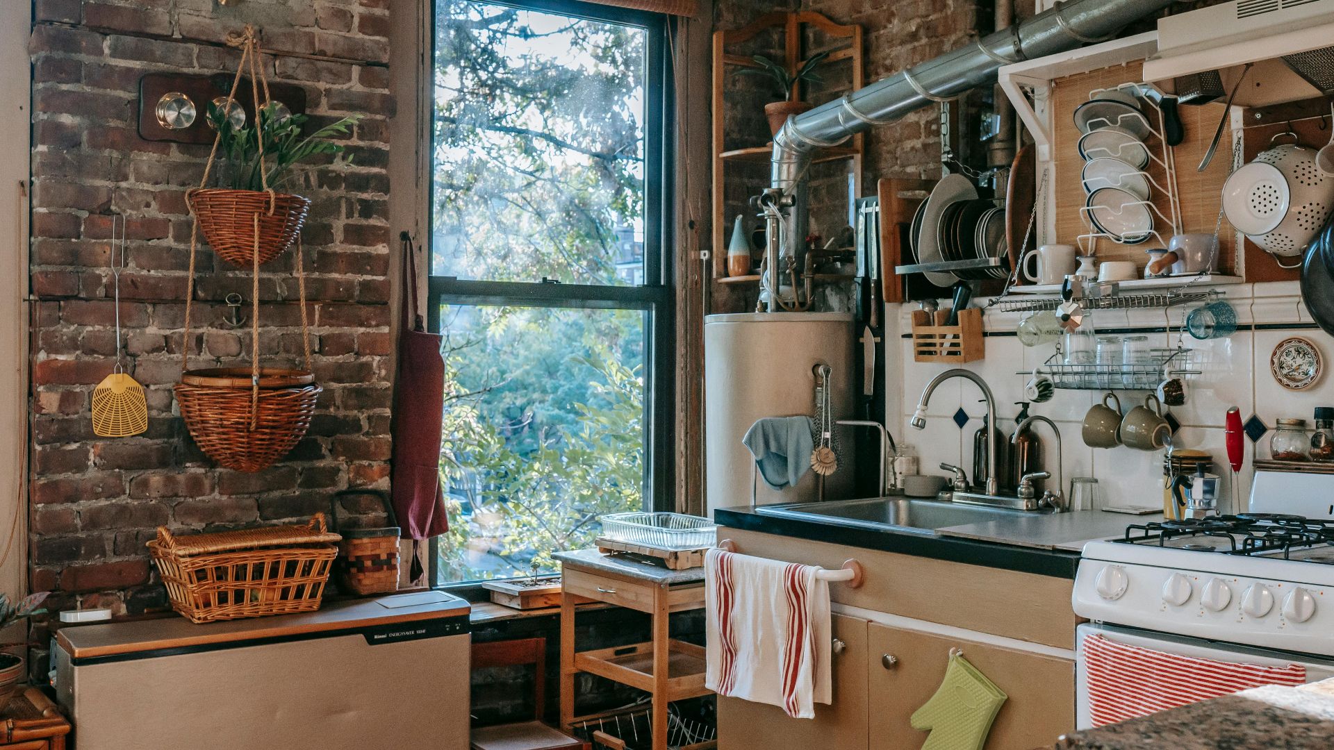 Charming rustic kitchen featuring wooden decor, exposed brick, and appliances with a sunlit window view.