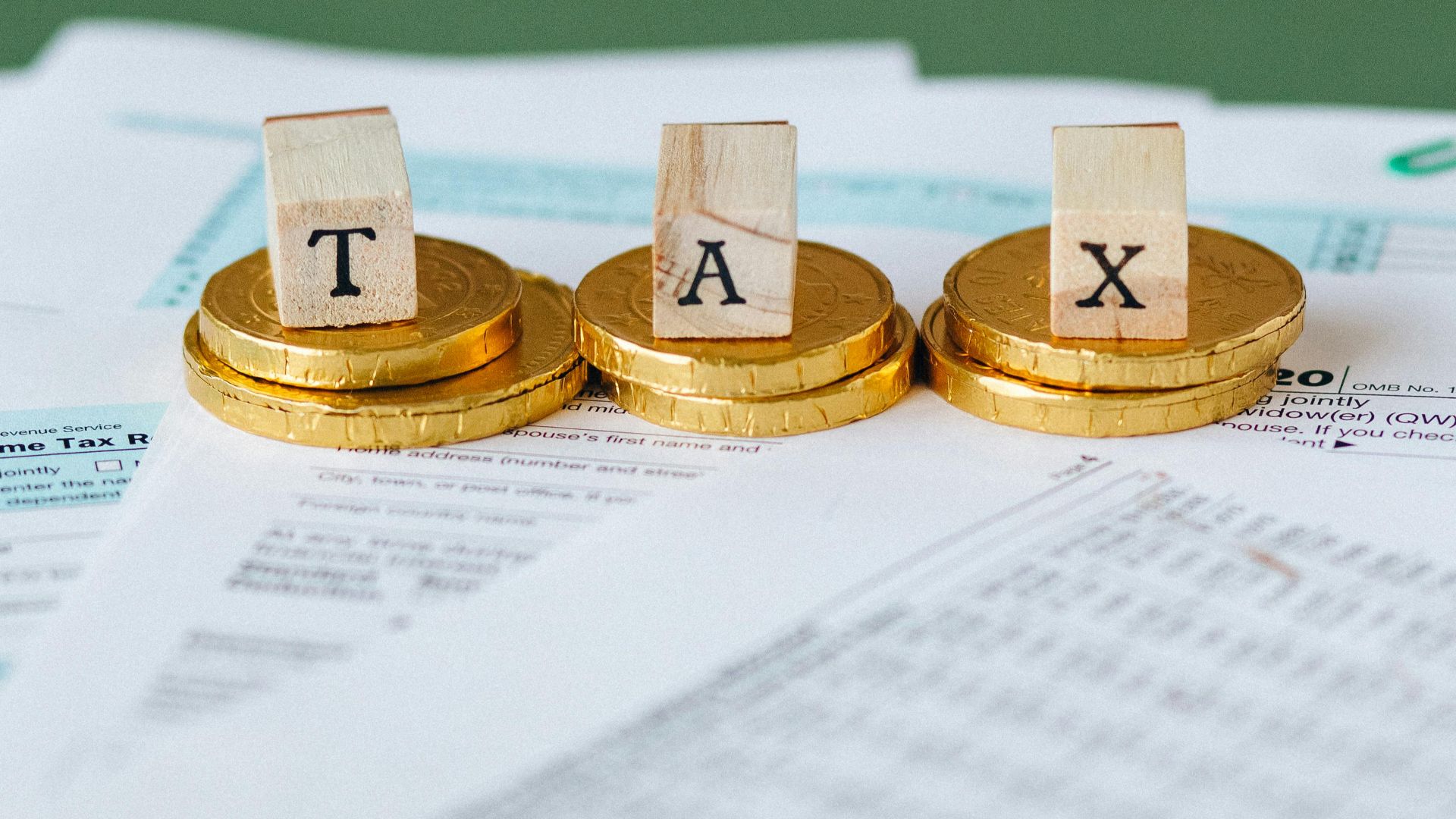 Staged image of gold coins with tax letter tiles on documents.