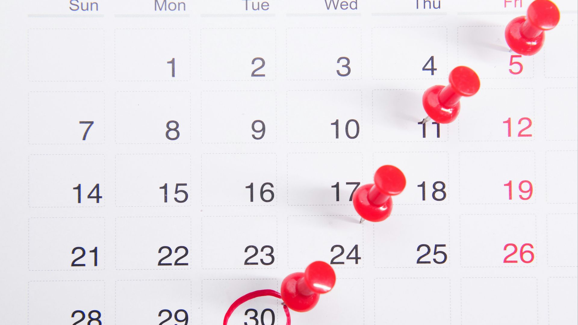 a calendar with red push buttons pinned to it