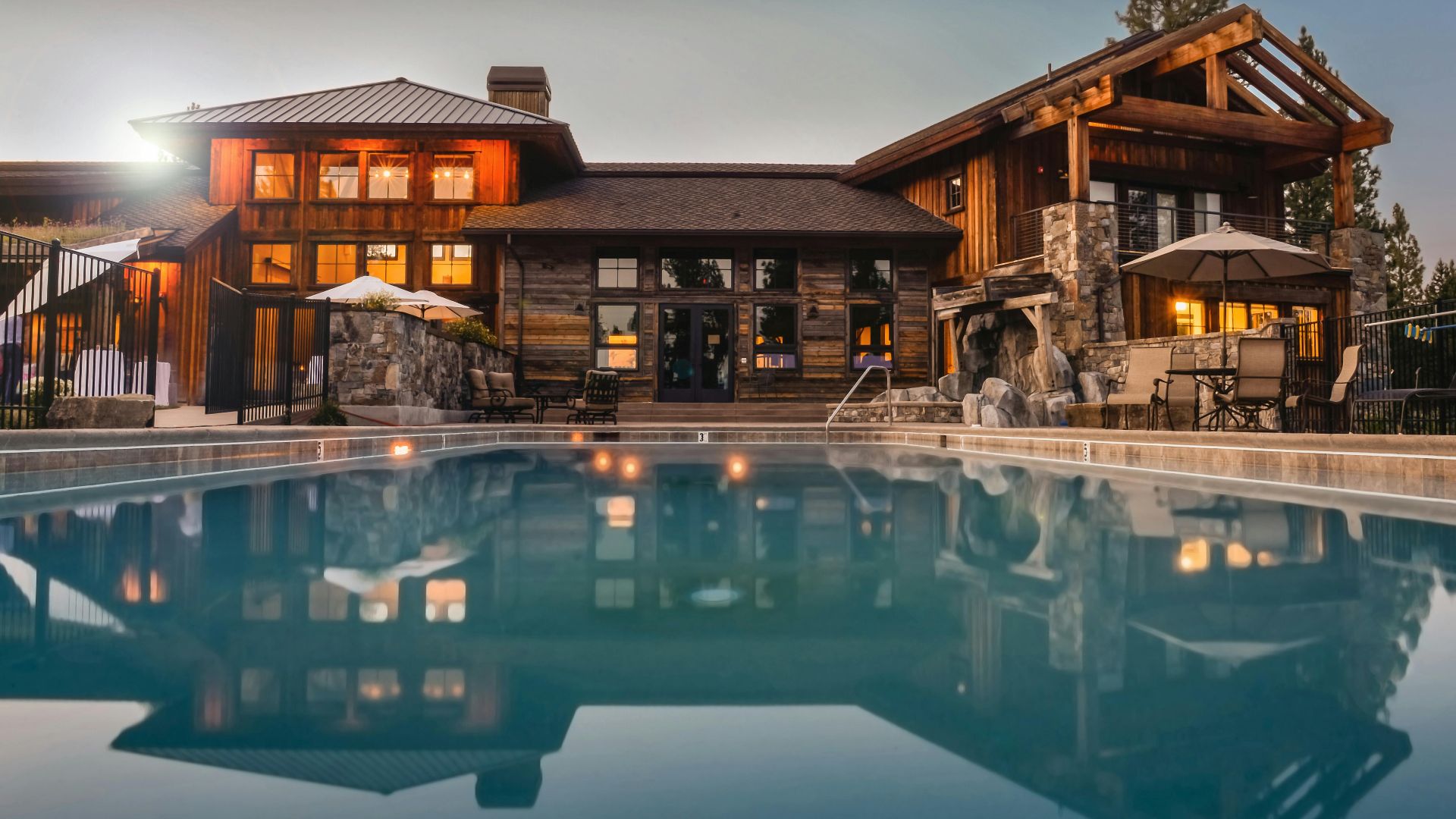 Stunning wooden villa with a large pool and cozy lights, perfect for a luxurious escape.