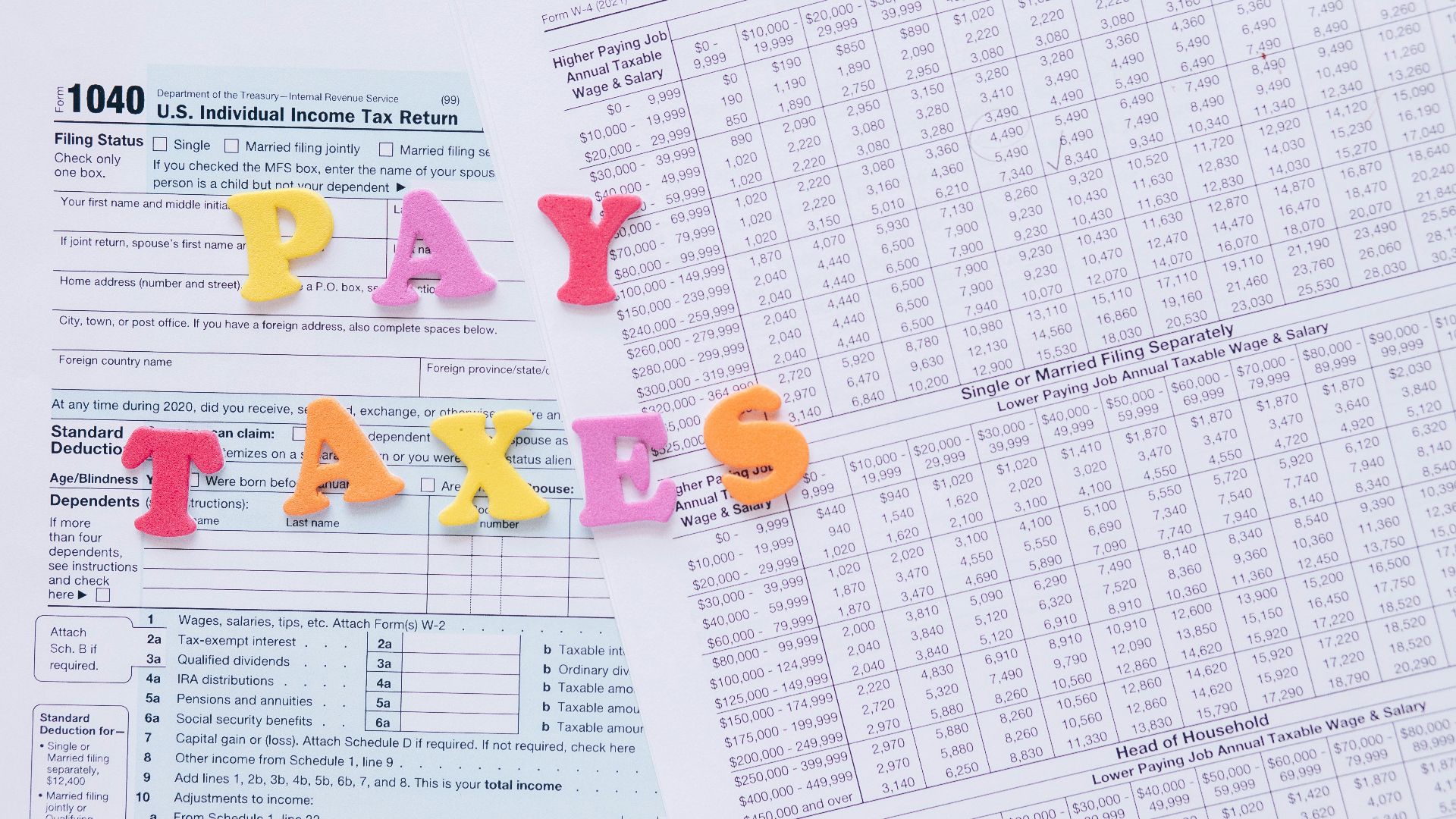 Close-up of U.S. tax forms with colorful 'PAY TAXES' letters emphasizing financial deadlines.
