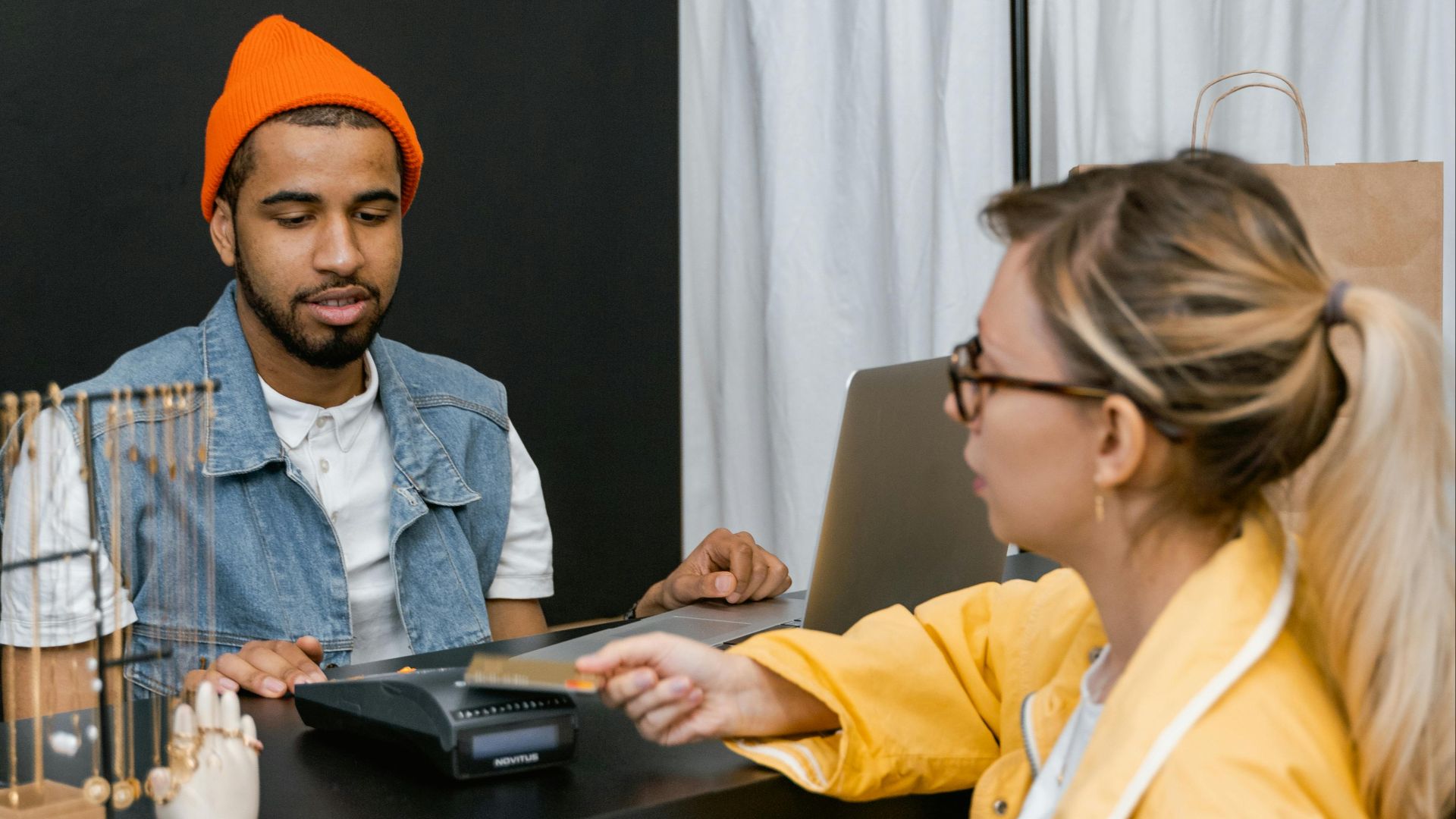 Customer using card for contactless payment at a fashion store counter with cashier.
