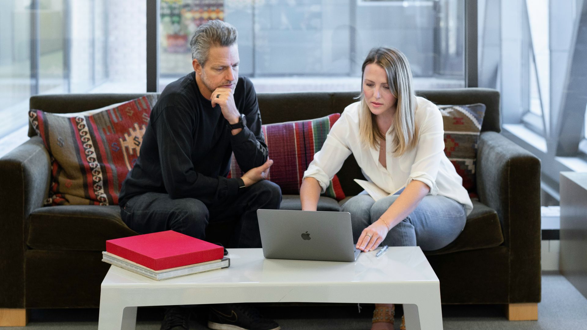 man and woman sitting on couch using macbook