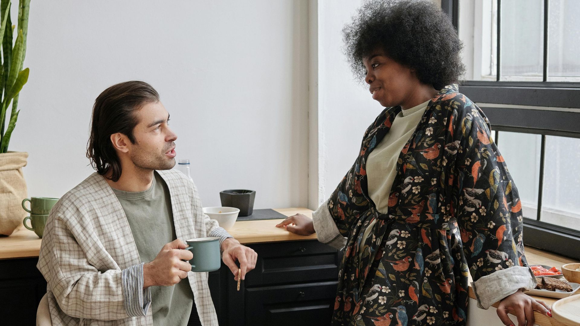 Couple enjoying morning coffee and conversation in cozy home setting.