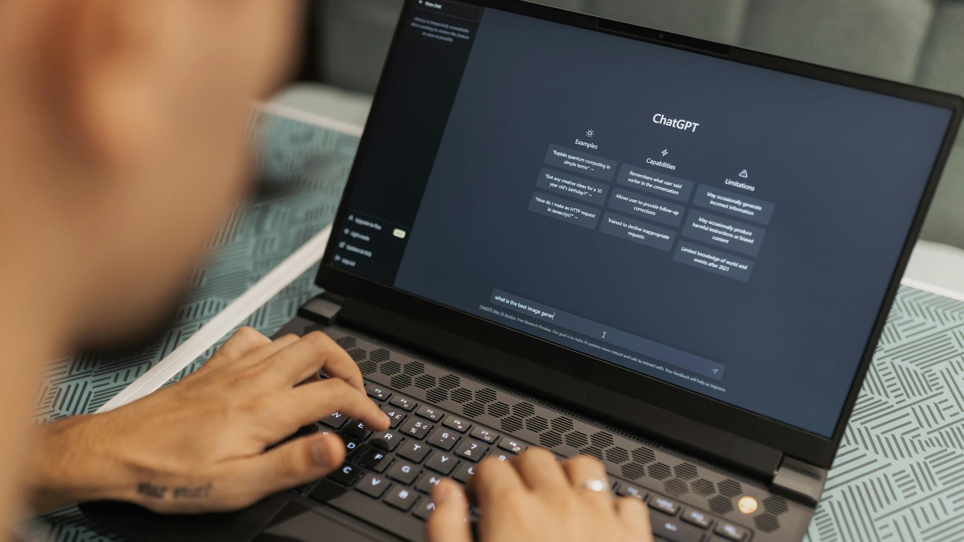 Close-up of a person typing on a laptop displaying the ChatGPT interface, emphasizing modern technology use.