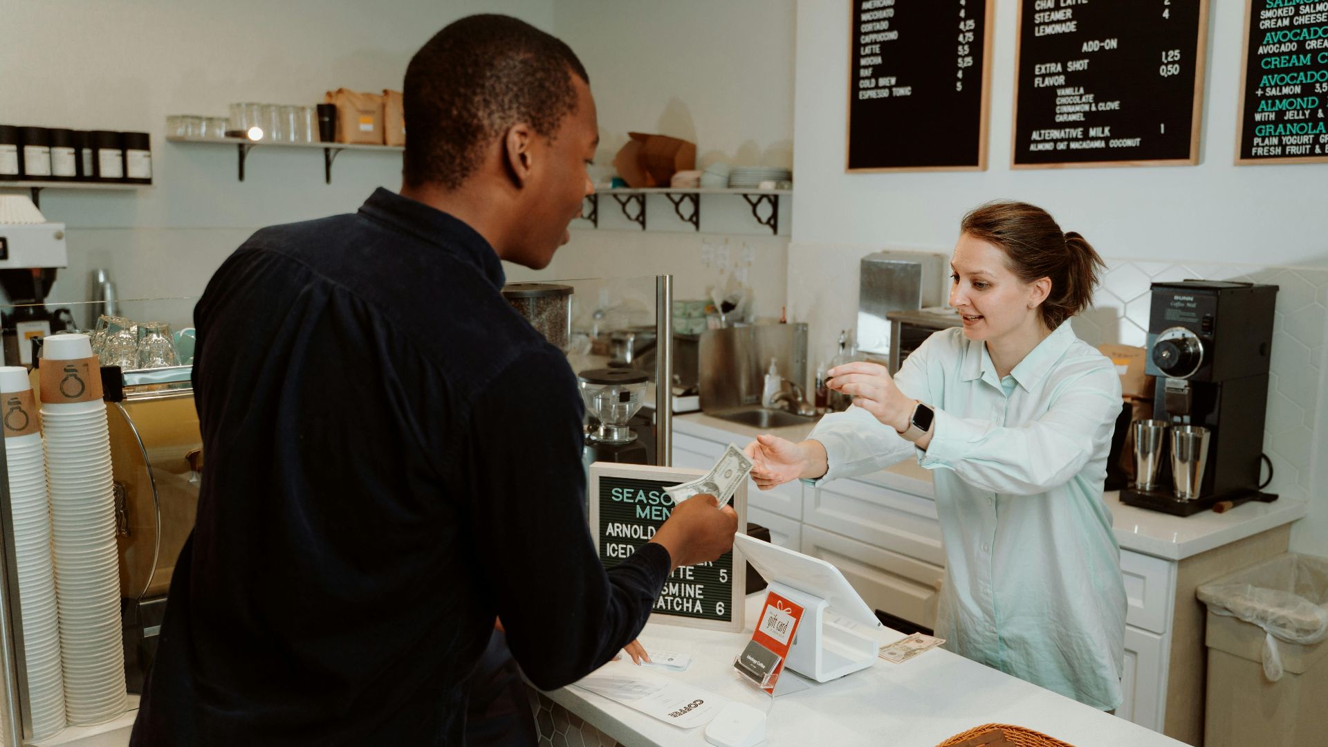 A customer pays for coffee at a café counter, transaction with barista.