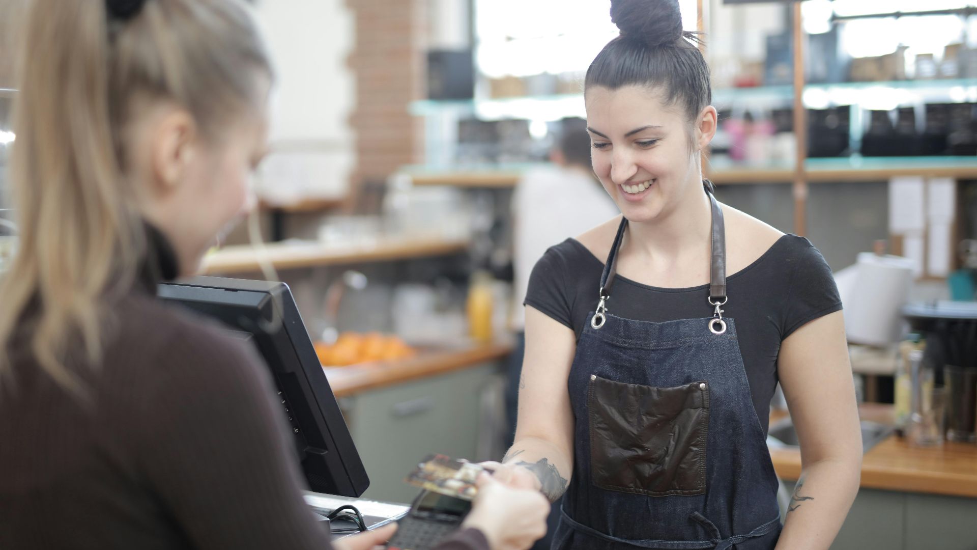 Smiling cashier helping customer with payment at store counter.