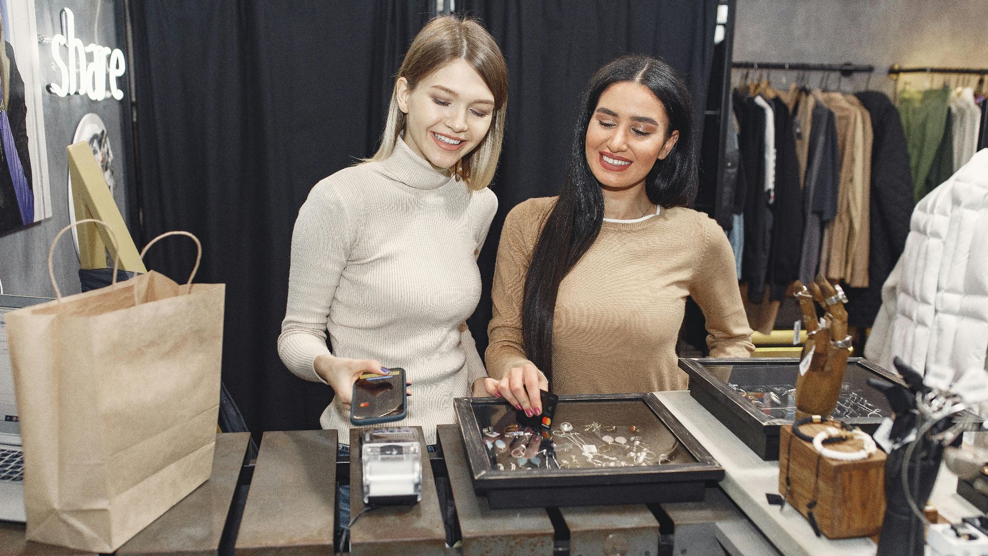 Two women making contactless payment in a chic fashion boutique.