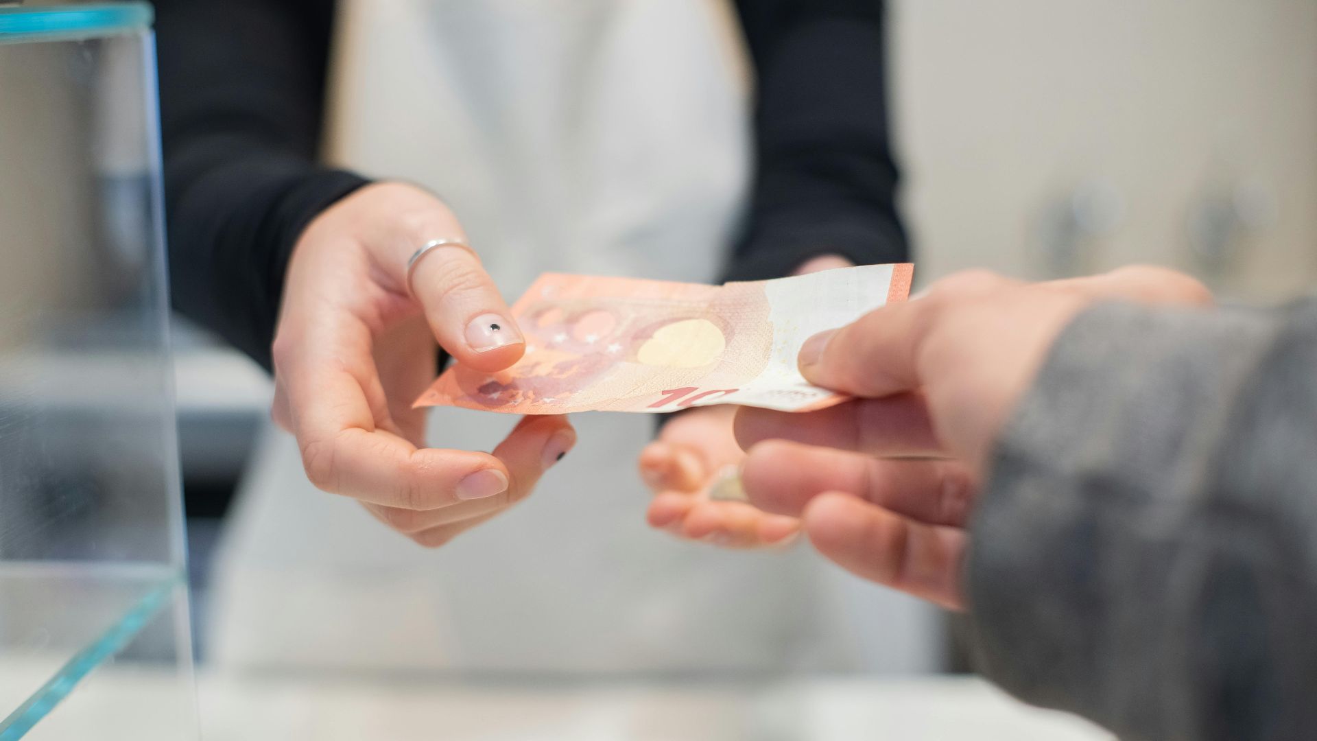 Close interaction of hands exchanging cash in a café setting. Business transaction detail.