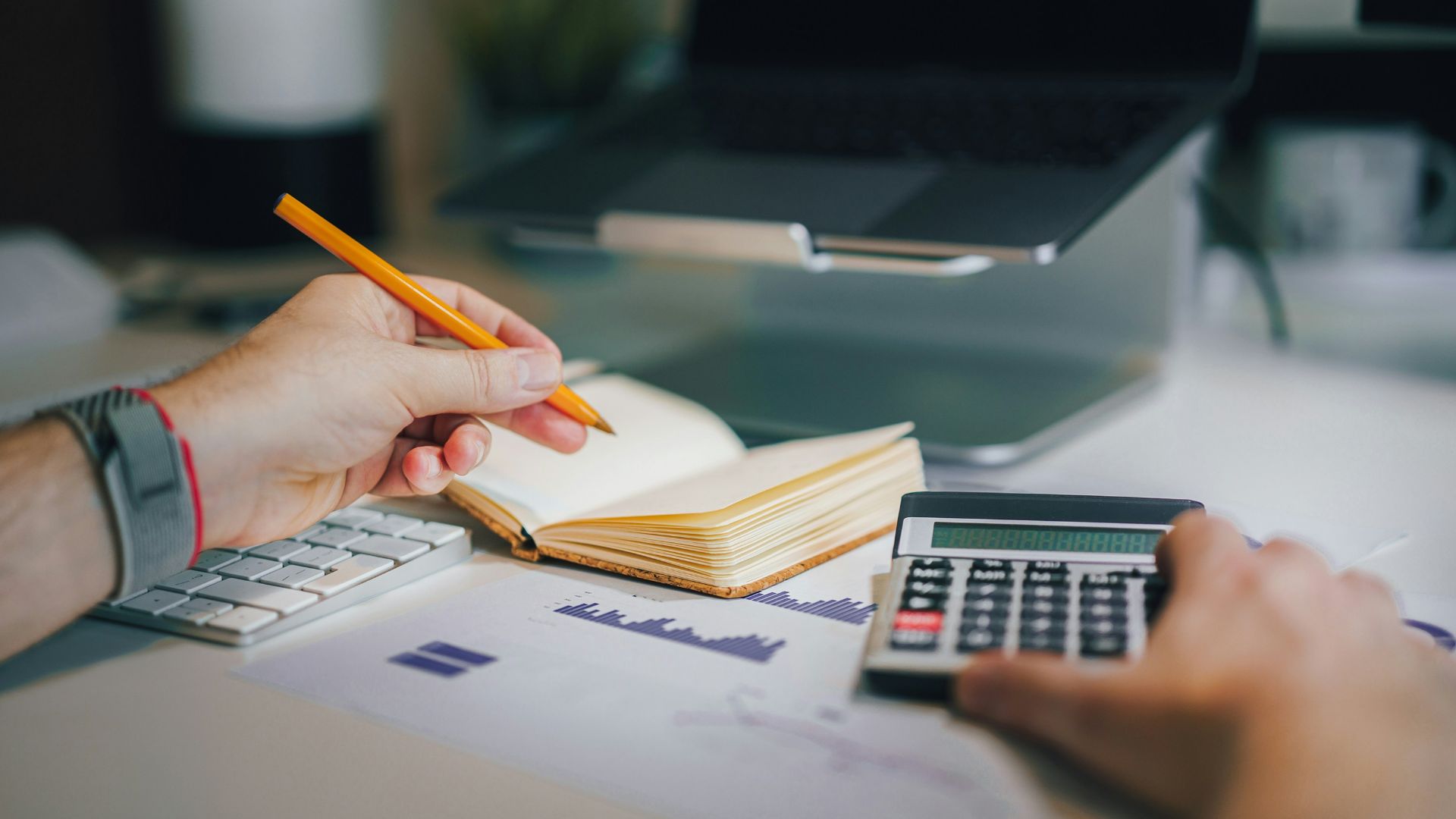 a person sitting at a desk with a calculator and a notebook